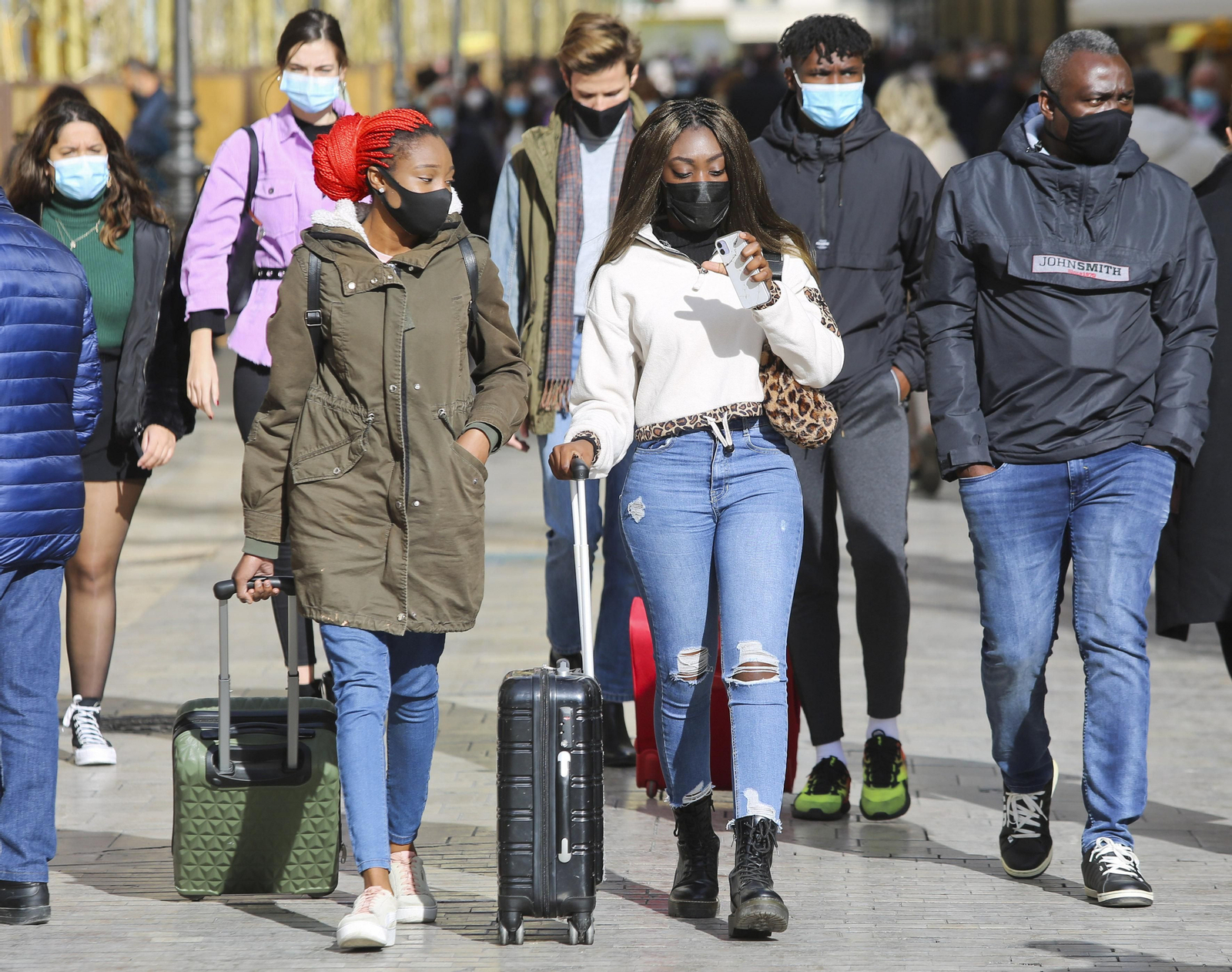 Turistas caminan con maletas por el centro de Málaga.