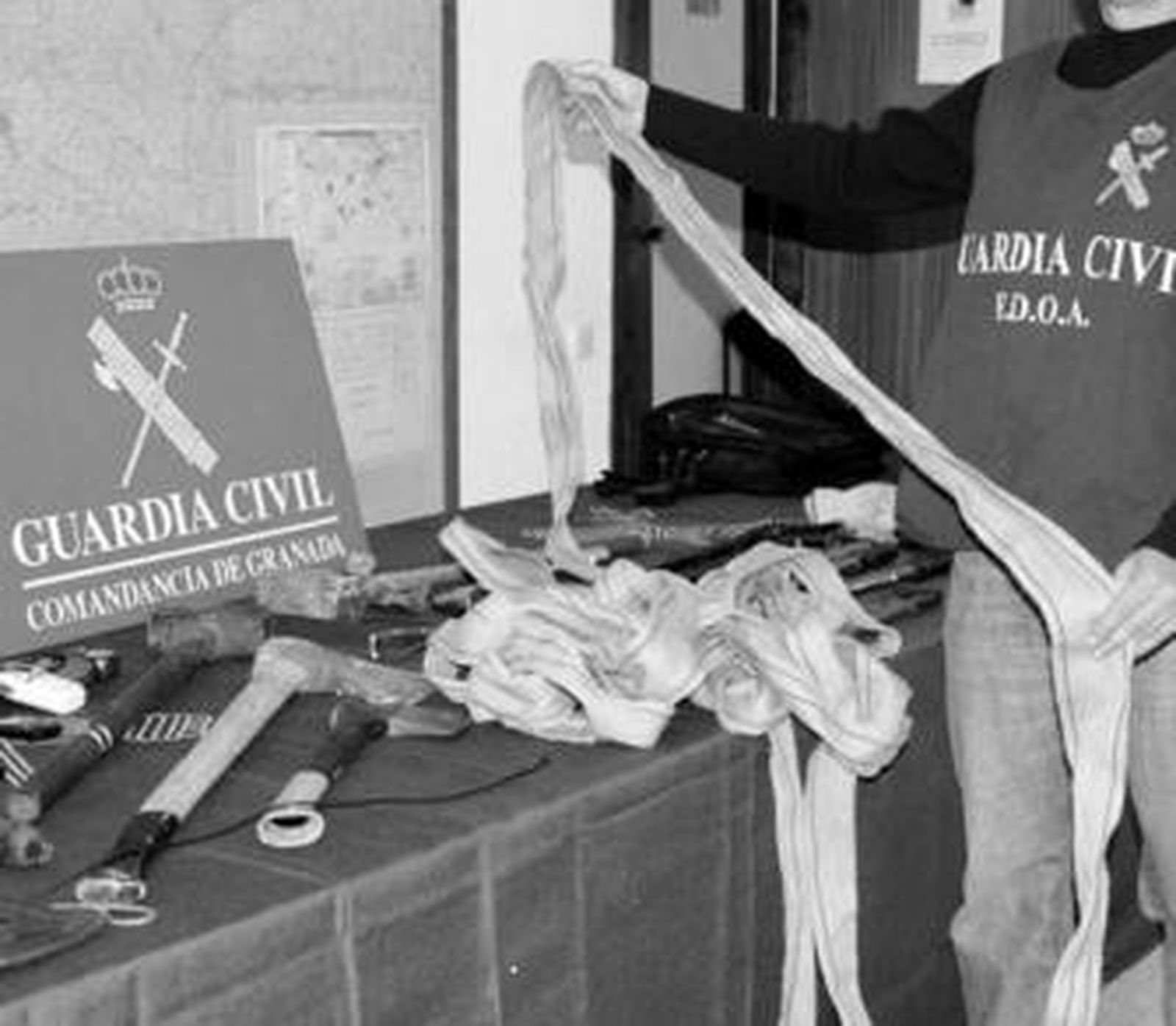 Un agente muestra el material intervenido a los asaltantes tras su detención.