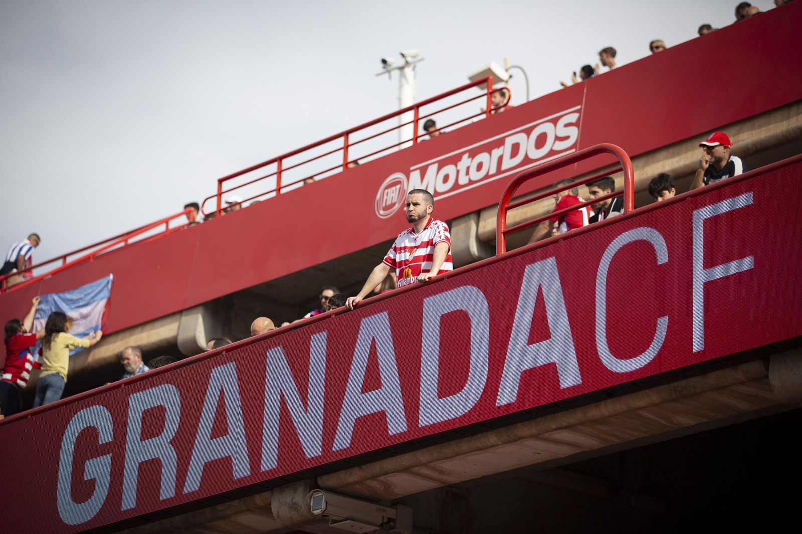 Un aficionados se asoma sobre el rótulo que pone Granada CF en el estadio