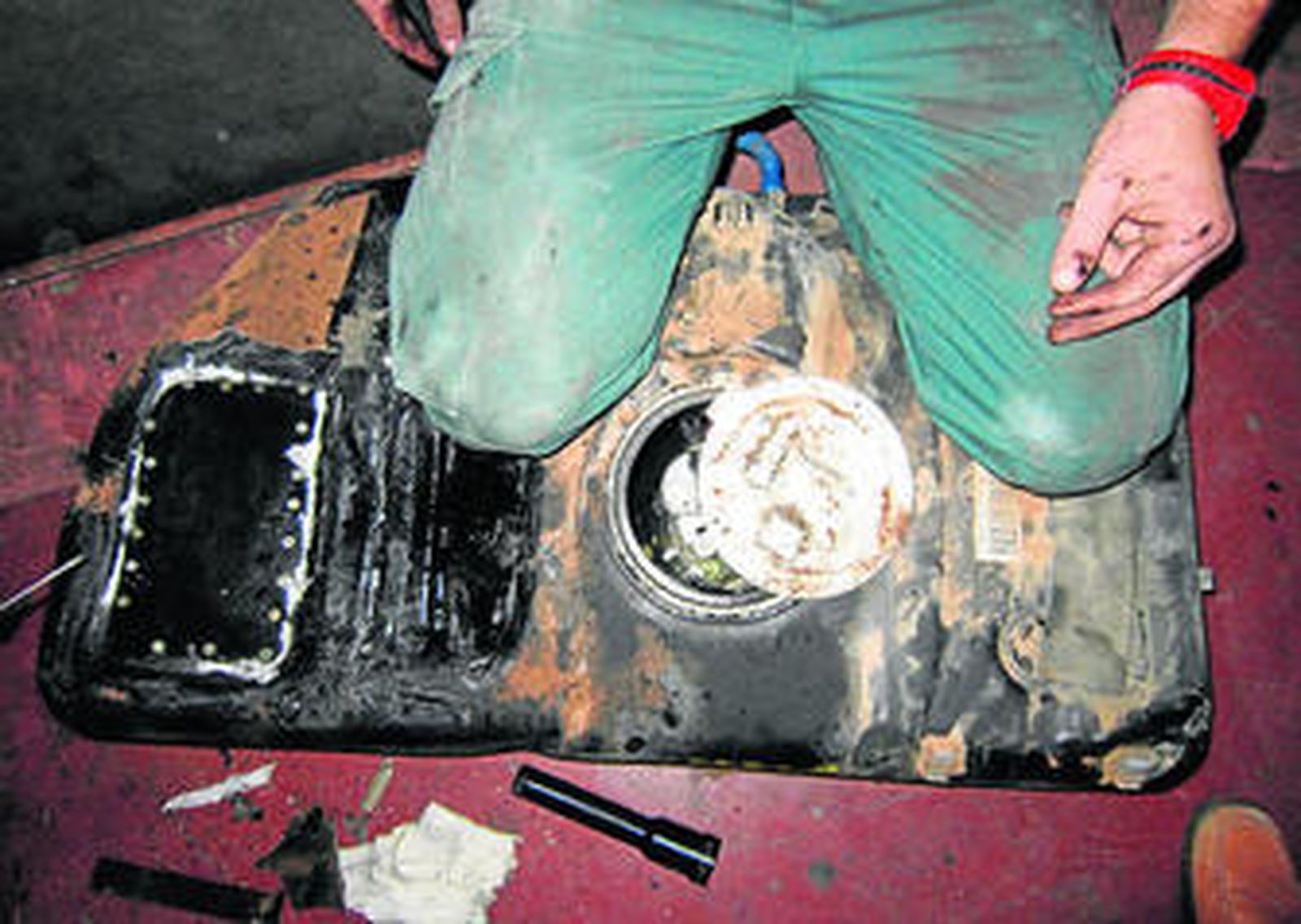 Un agente se arrodilla sobre el depósito de combustible al que se le había practicado un doble fondo.