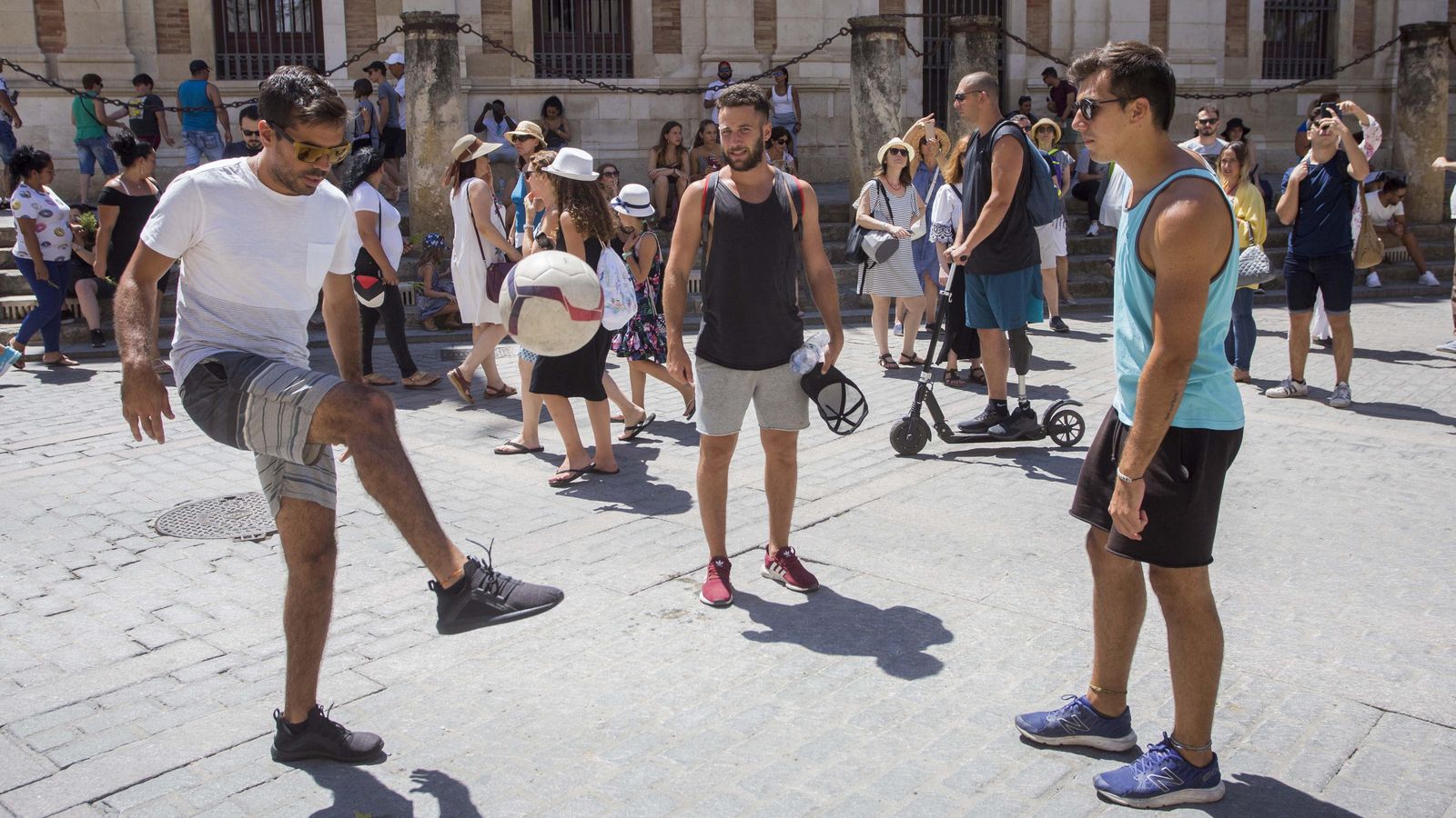 Turistas juegan al fútbol en la Plaza del Triunfo.
