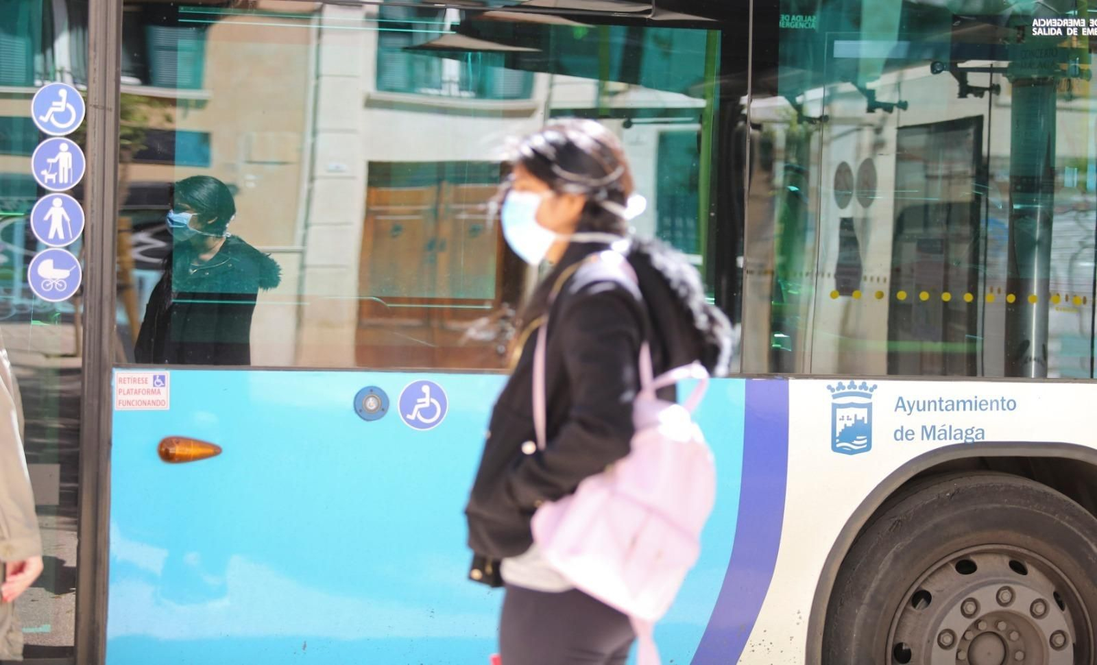Una mujer con mascarilla pasa por delante de un autobús de la EMT.