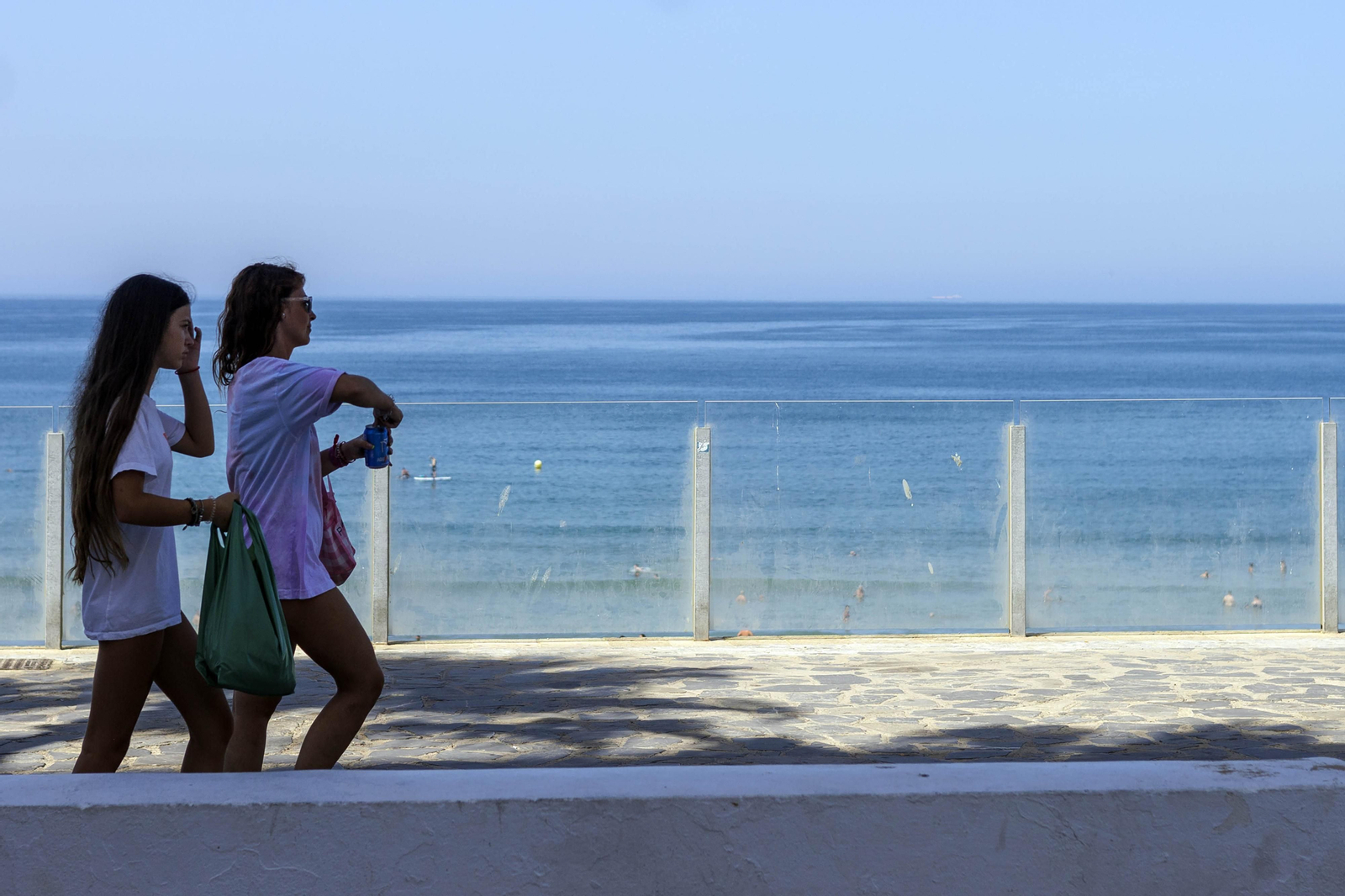Dos jóvenes pasan por delante de las mamparas acristaladas llenas de suciedad.