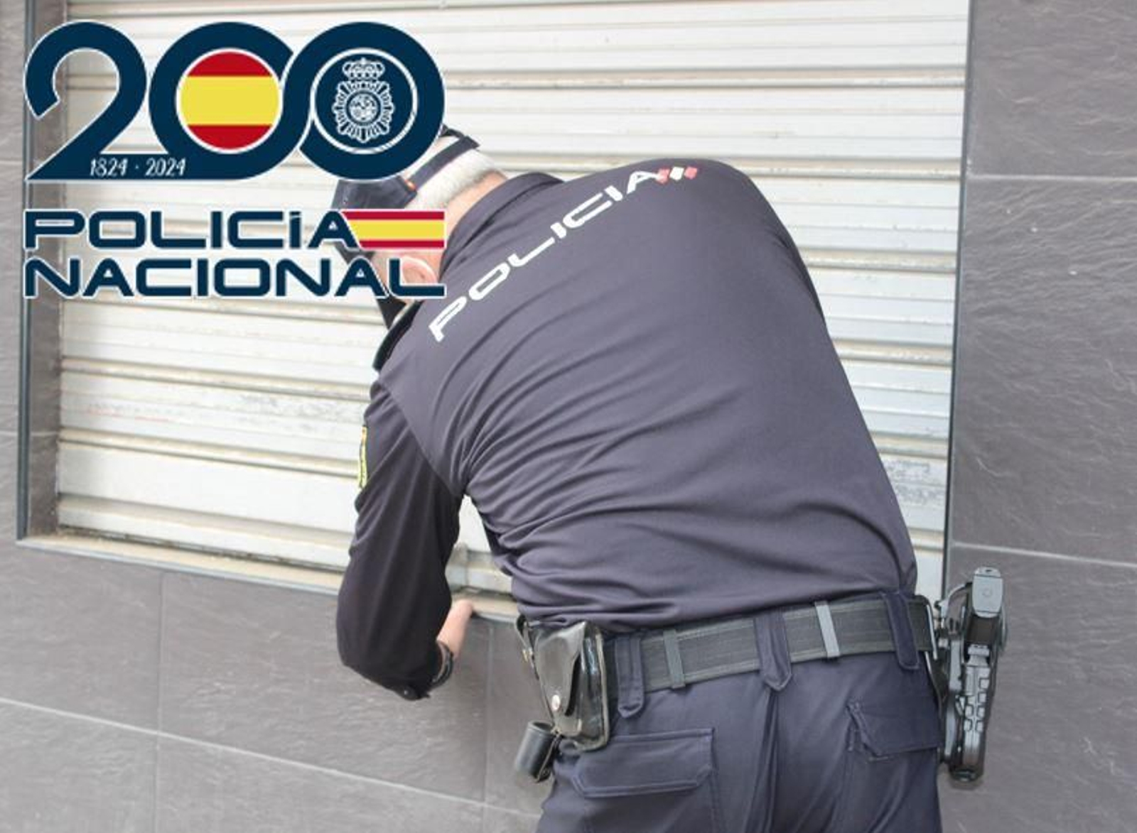 Un agente de la Policía Nacional inspecciona una ventana de un local cerrado