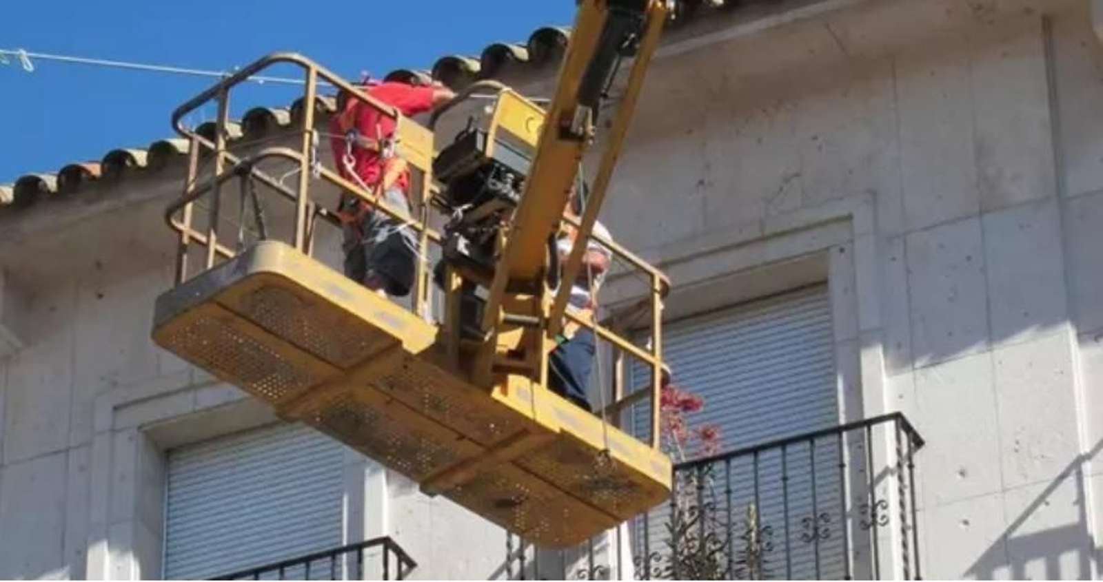 Dos trabajadores, en una grúa a pleno sol.