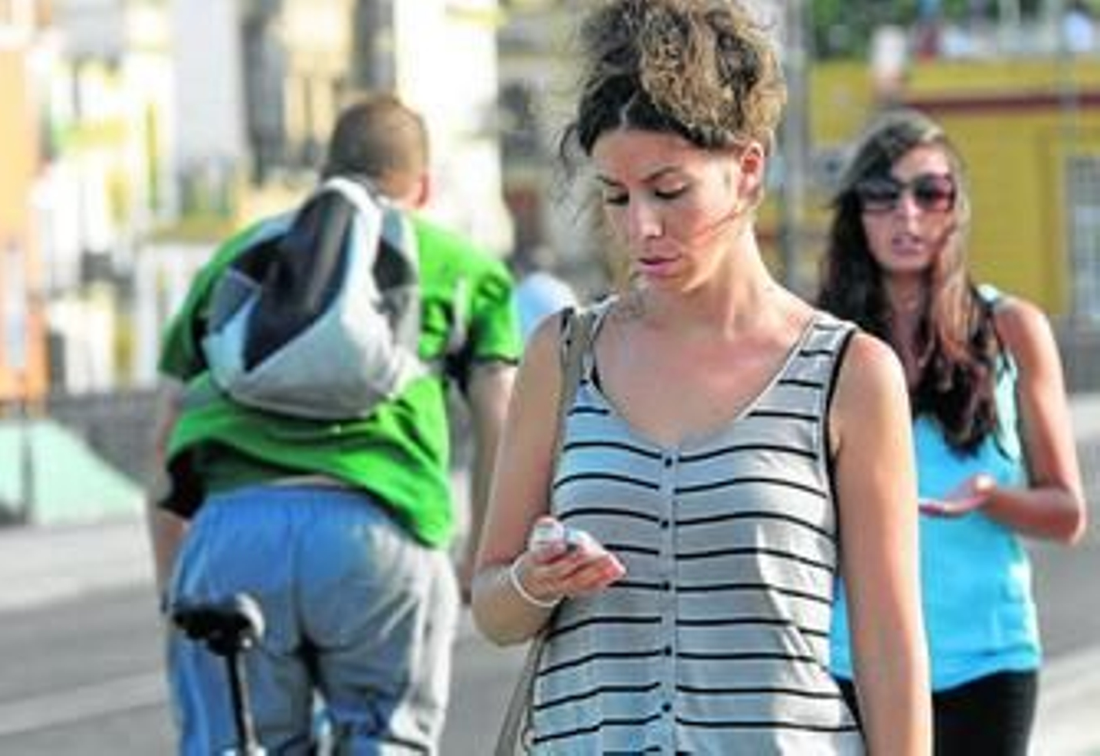 Una joven atiende su teléfono móvil por el puente de Triana, junto al carril-bici.