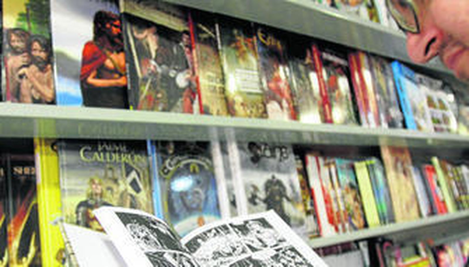 Un lector hojea un cómic en la tienda de Player Versus Player de Cádiz.