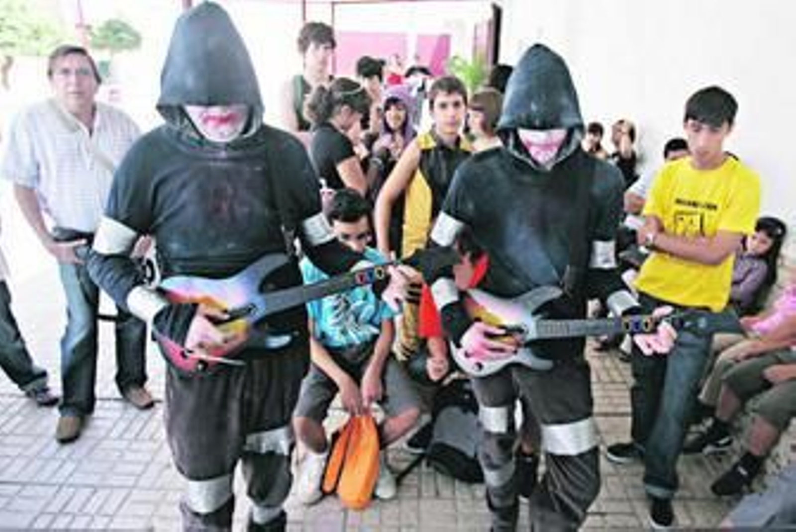 Dos jóvenes siguen el ritmo de la música con las guitarras de un videojuego.
