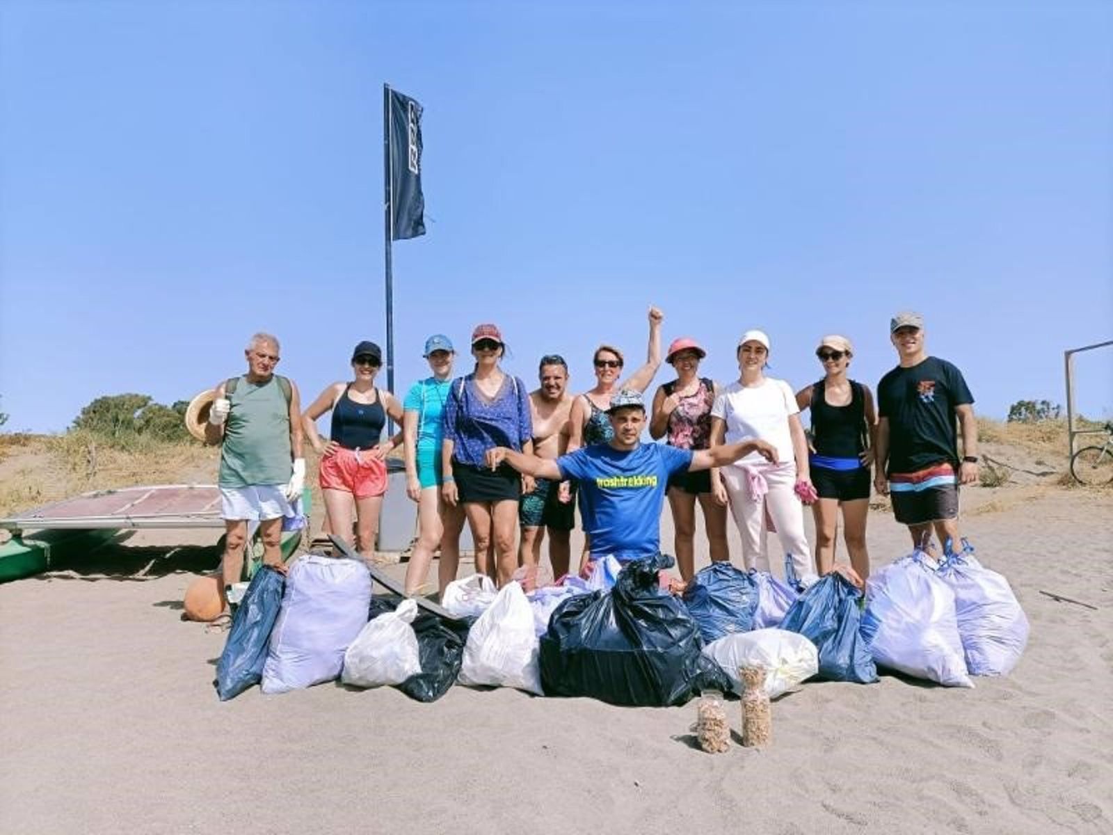 Un grupo de ciudadanos posa tras recoger basura en una playa.