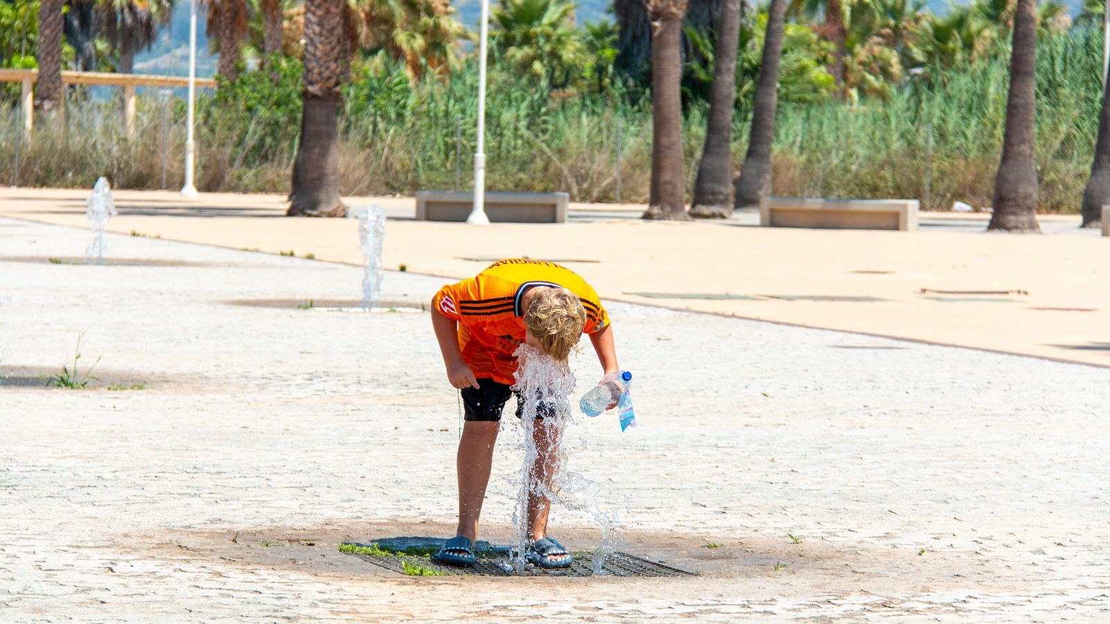 Un niño se resfresca en una fuente de Playa Granada para sobrellevar el calor