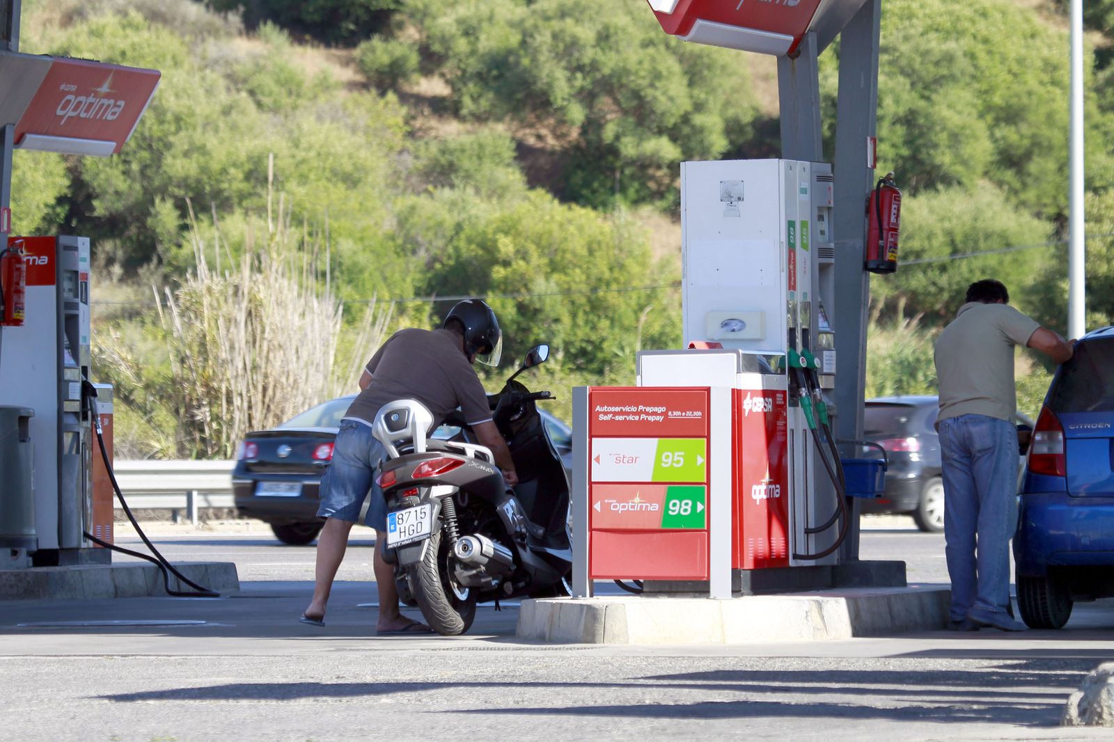 Varias personas repostan sus vehículos en la gasolinera.