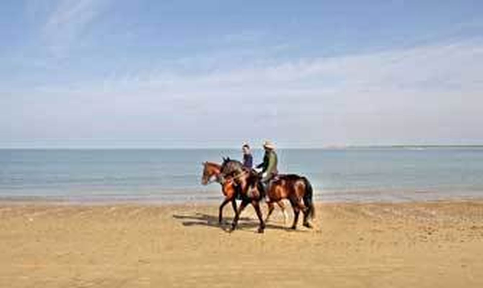 Dos jinetes con sus caballos paseando en la mañana de ayer por la sanluqueña playa de Las Piletas. /Joaquín Pino