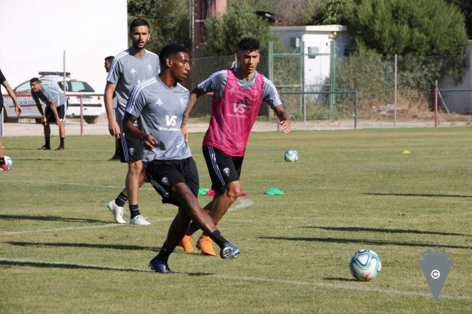 Seth Vega golpea el balón en presencia de Rhyner y Kecojevic, durante un entreno en el Municipal de Benalup.