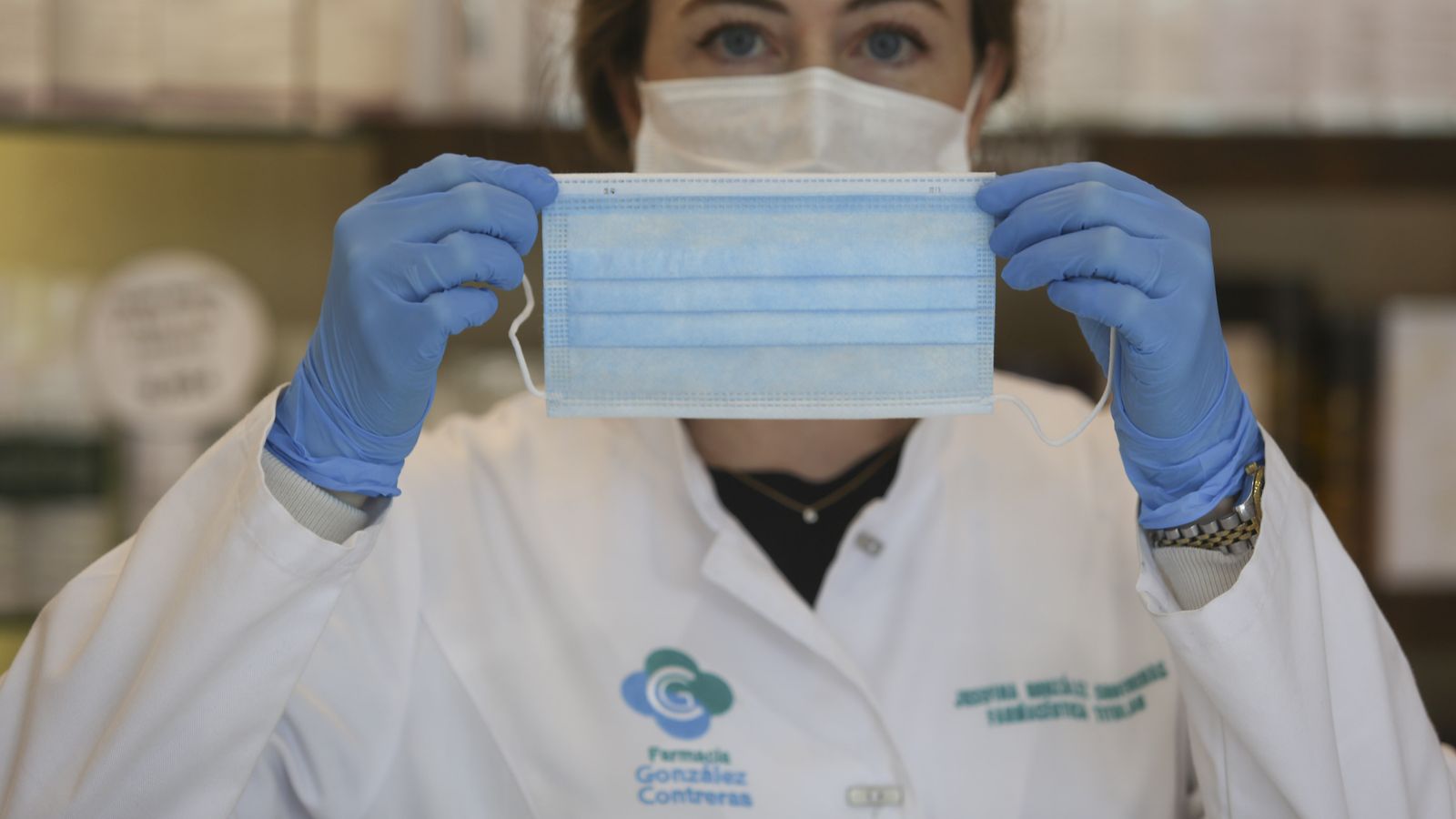 Una farmacéutica muestra una de las mascarillas que tiene a la venta.