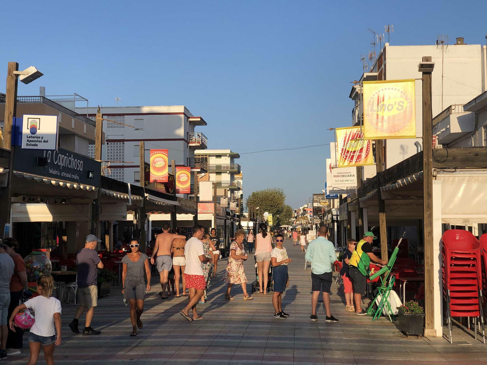 La avenida de Castilla de La Antilla llena de veraneantes que pasen por sus calles y sus comercios.