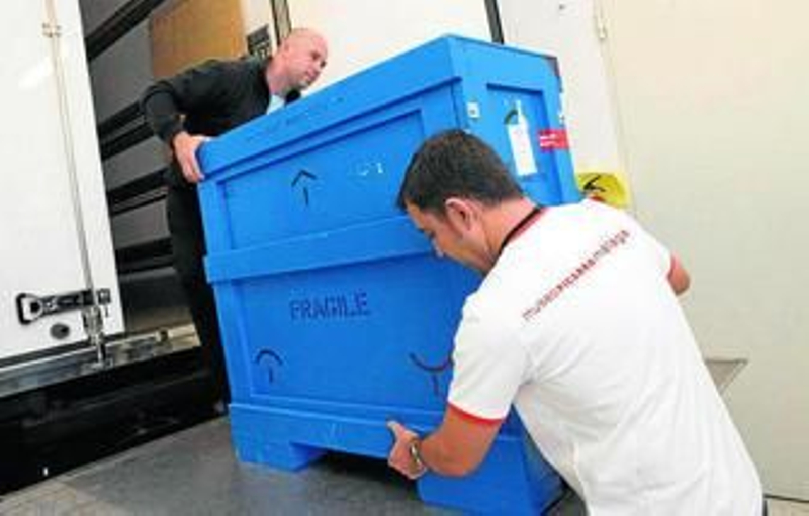 Operarios trasladan el lienzo de George Grosz tras su llegada al Picasso el pasado jueves.