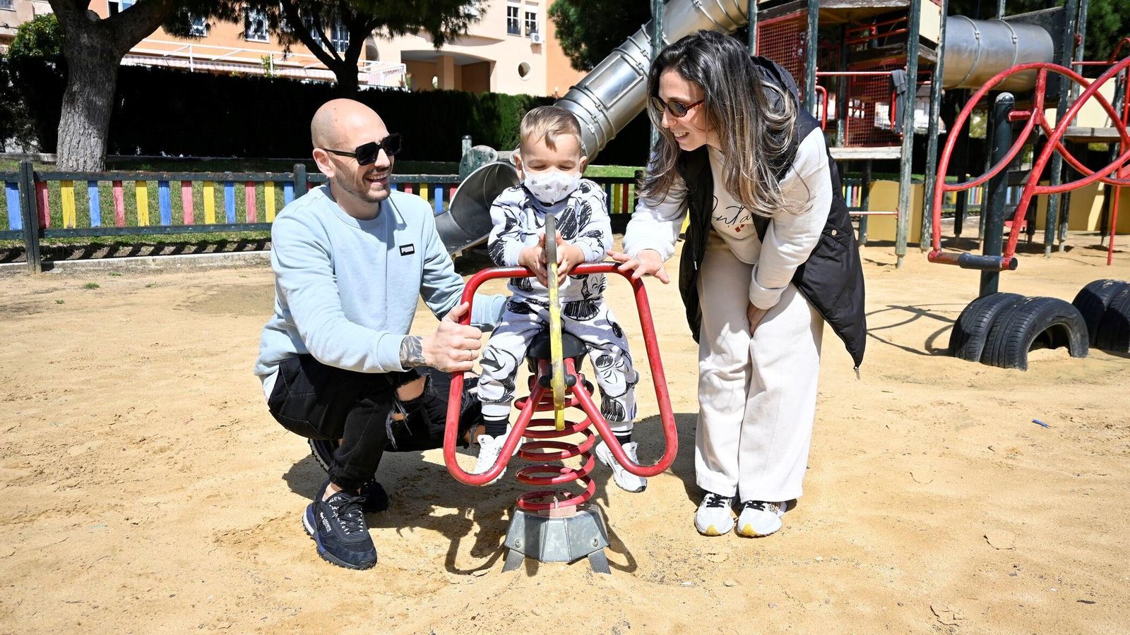 Fabio y sus padres disfrutan juntos en un parque infantil.