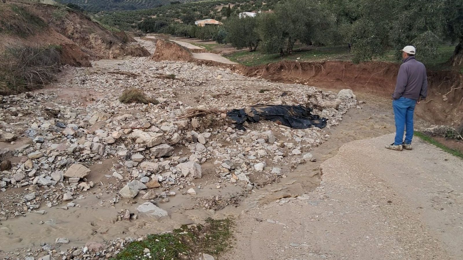 Un agricultor observa uno de los caminos destrozados por la lluvia.