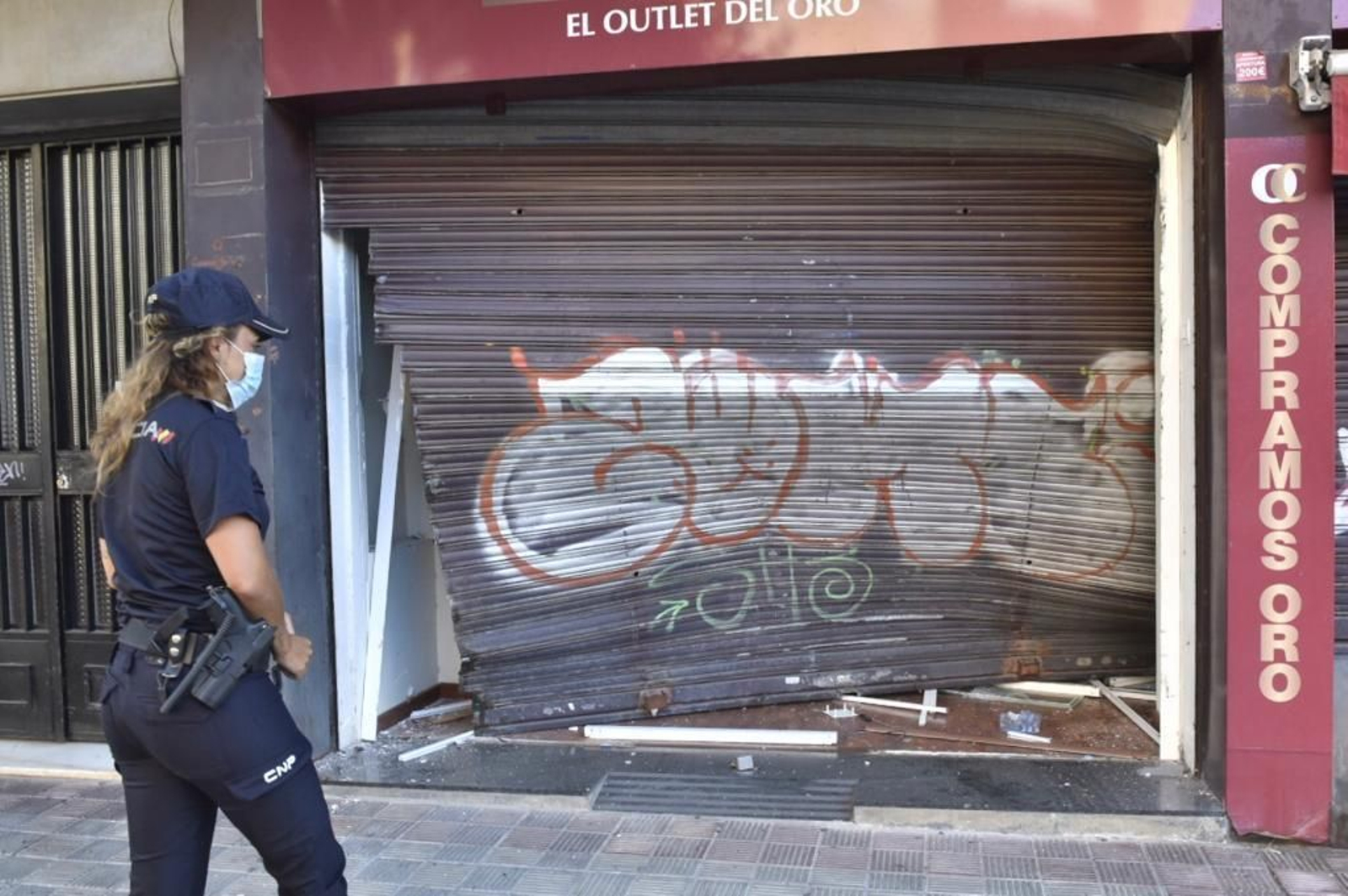 Una policía nacional, ante la puerta de la joyería que ha sufrido el alunizaje.
