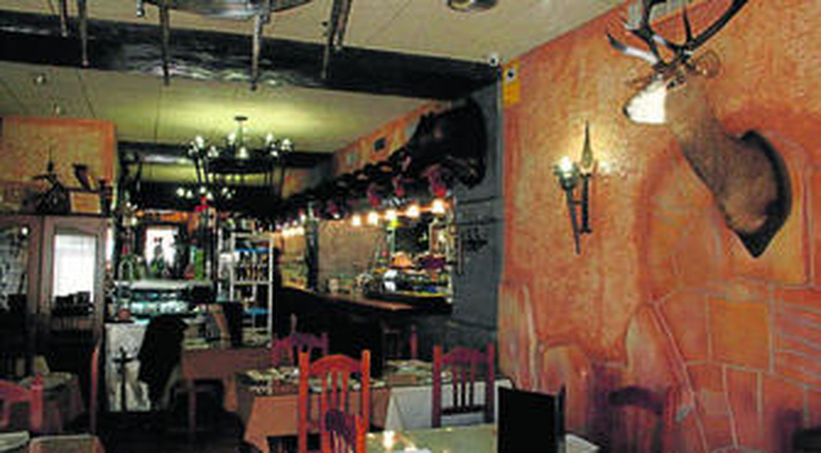Vista parcial de la barra desde el interior del restaurante, adornado con diferentes motivos de caza. En la calle peatonal tiene también mesas para quien prefiera estar al aire libre.