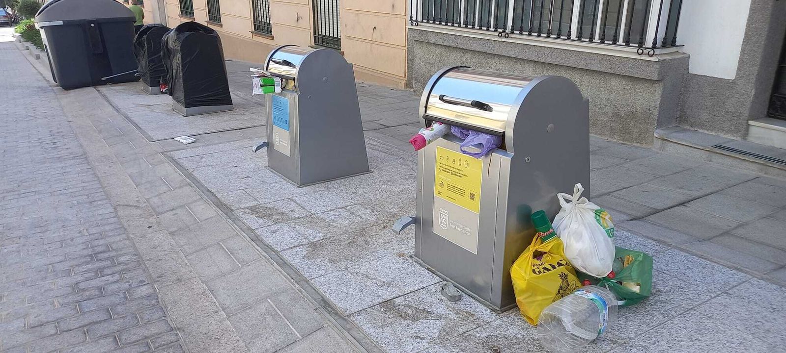 Contenedores rebosante y otros precintados, en la calle Héroes de Baleares.