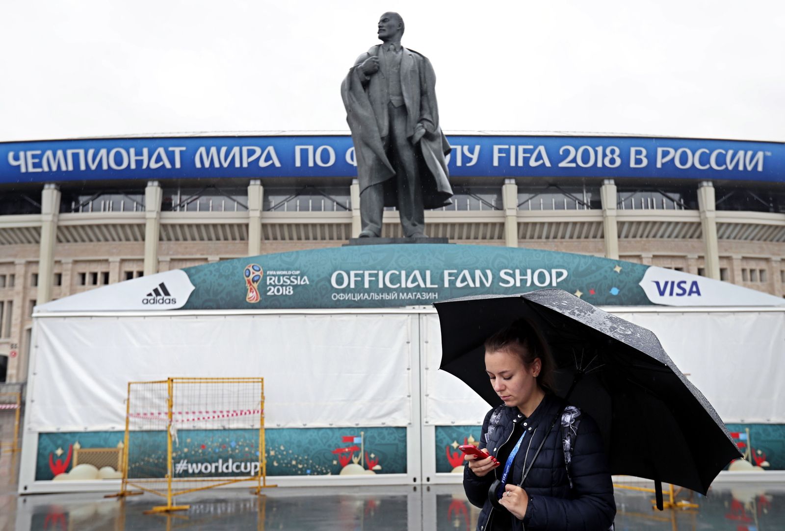 Una joven mira su móvil bajo la lluvia, ayer, ante una estatua de Lenin en Moscú.