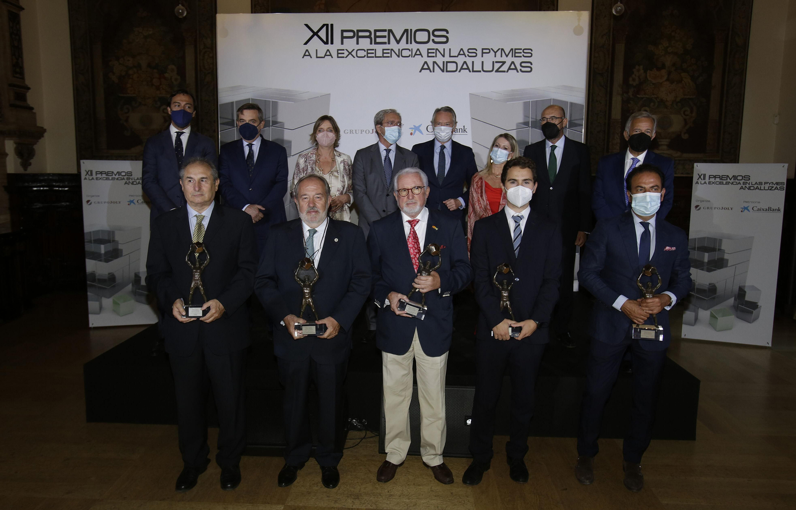 Delante, los galardonados: Antonio Cabrera, CEO de Viafirma; Alfonso Carmona, director médico y fundador de Grupo IHP; Juan Valle, fundador de Juvasa; Arturo López, director de Desarrollo de Negocio de ISR, y Estanislao Martínez, presidente de AGQ Labs. Detrás, Guillermo Martín, director comercial de Banca de Empresas de CaixaBank en Andalucía Occidental y Extremadura y presidente del jurado; Pablo Pérez Fernandez, director ejecutivo del programa Pymes de San Telmo Business School; María Jesús Catalá, directora territorial de Caixabank en Andalucía Occidental y Extremadura; Rogelio Velasco, consejero de Transformación Económica, Industria, Conocimiento y Universidades; José Joly, presidente de Grupo Joly; Rocío Mesa, directora de Transformación Digital de Grupo Joly; Francisco Ferraro, catedrático de Economía, miembro del Consejo Editorial de Grupo Joly y secretario del jurado; y Jorge Segura, consultor de empresas.