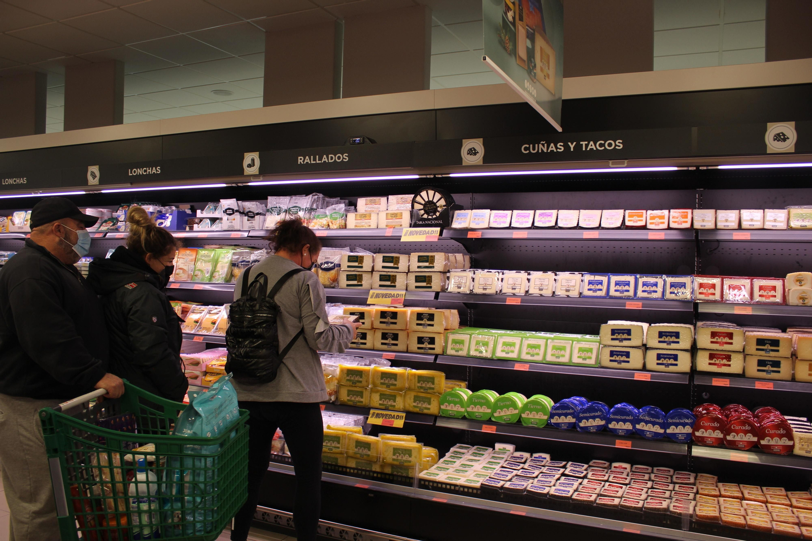 Unos clientes eligen entre el surtido de quesos de un supermecado en Chiclana.