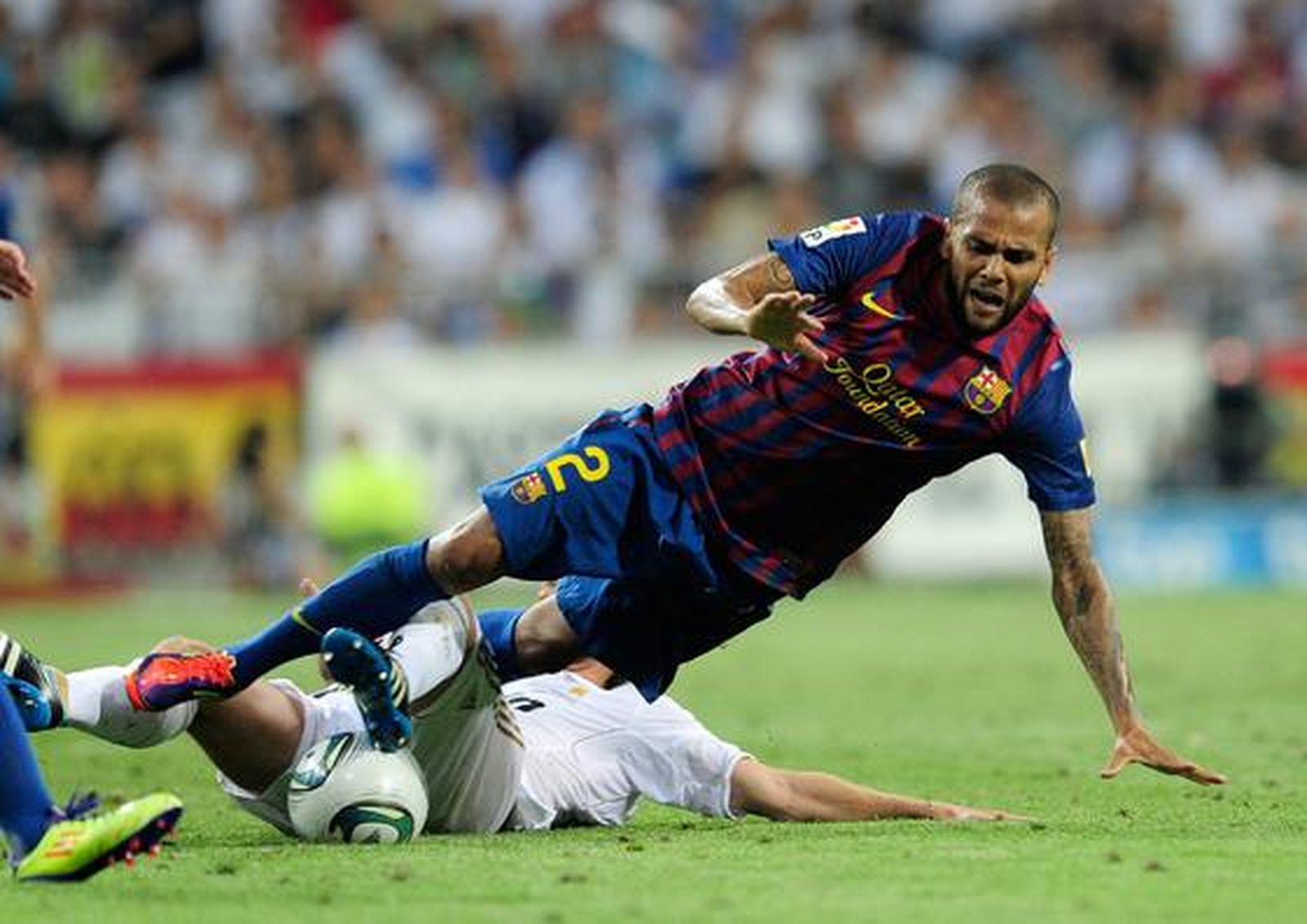 Dani Alves cae al césped tras una entrada. / AFP