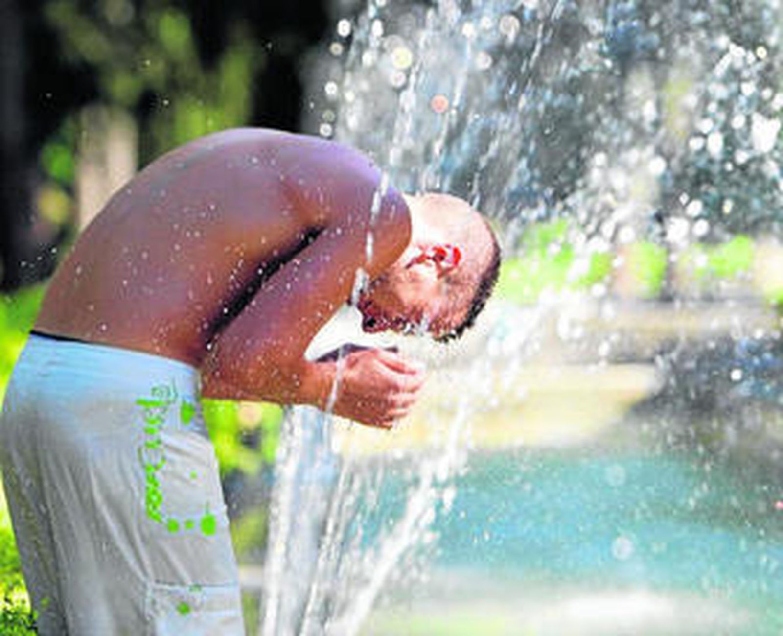 Un joven se refresca en una fuente, ayer por la tarde.