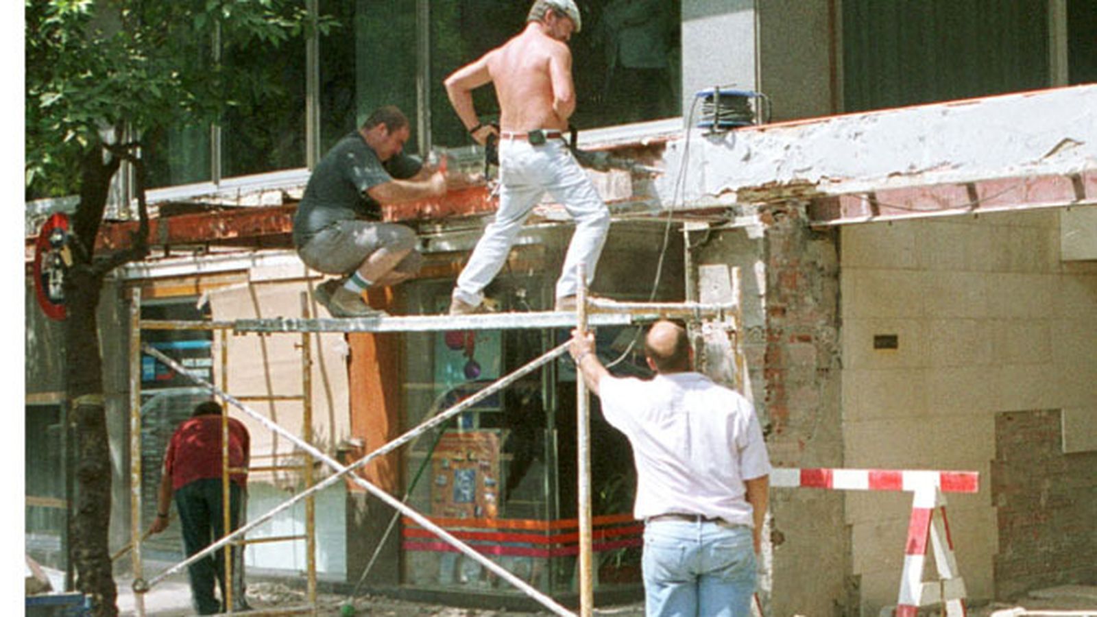 Varios albañiles, sobre un andamio, en una obra.