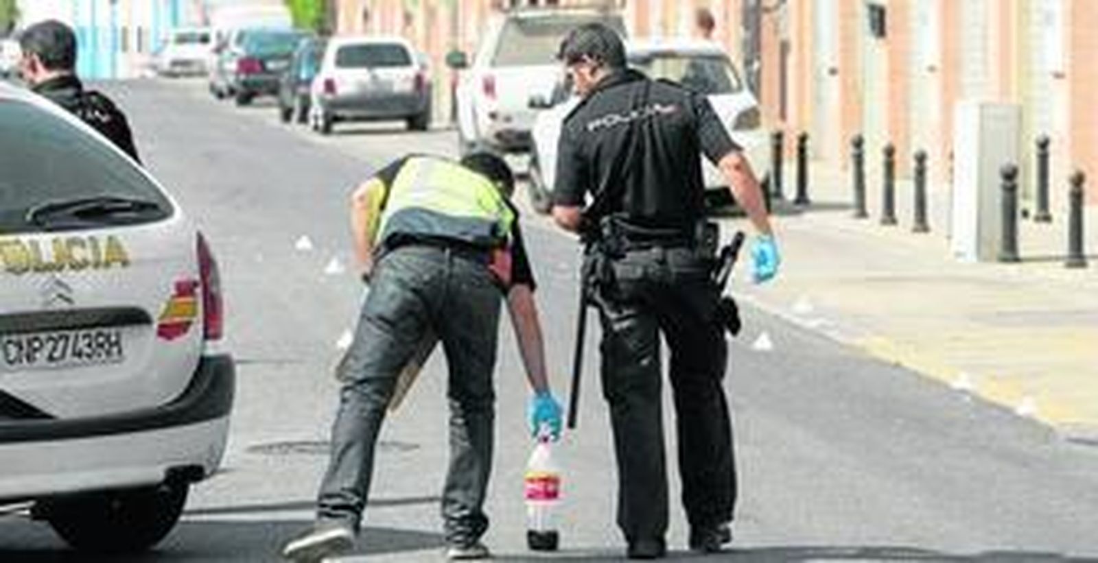 Dos agentes examinan una botella de refresco en el lugar de la reyerta, ayer en el polígono industrial Calonge.