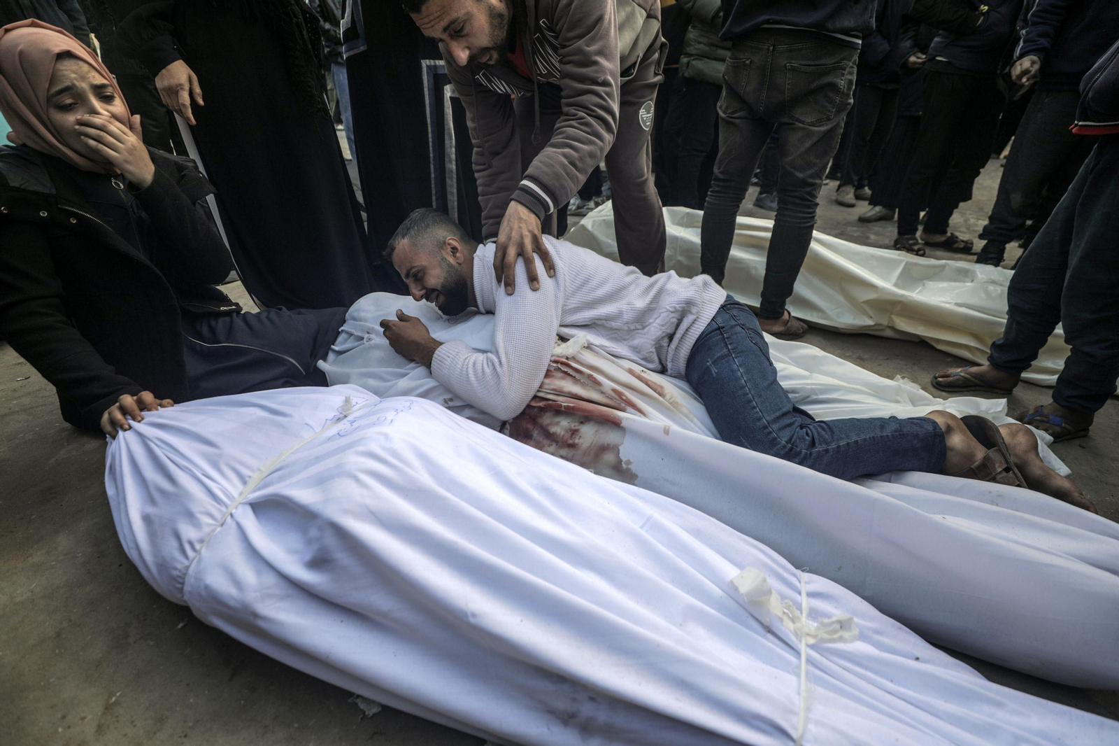 Familiares de los fallecidos en los ataques aéreos israelíes lloran junto a sus cuerpos en Deir al Balah.
