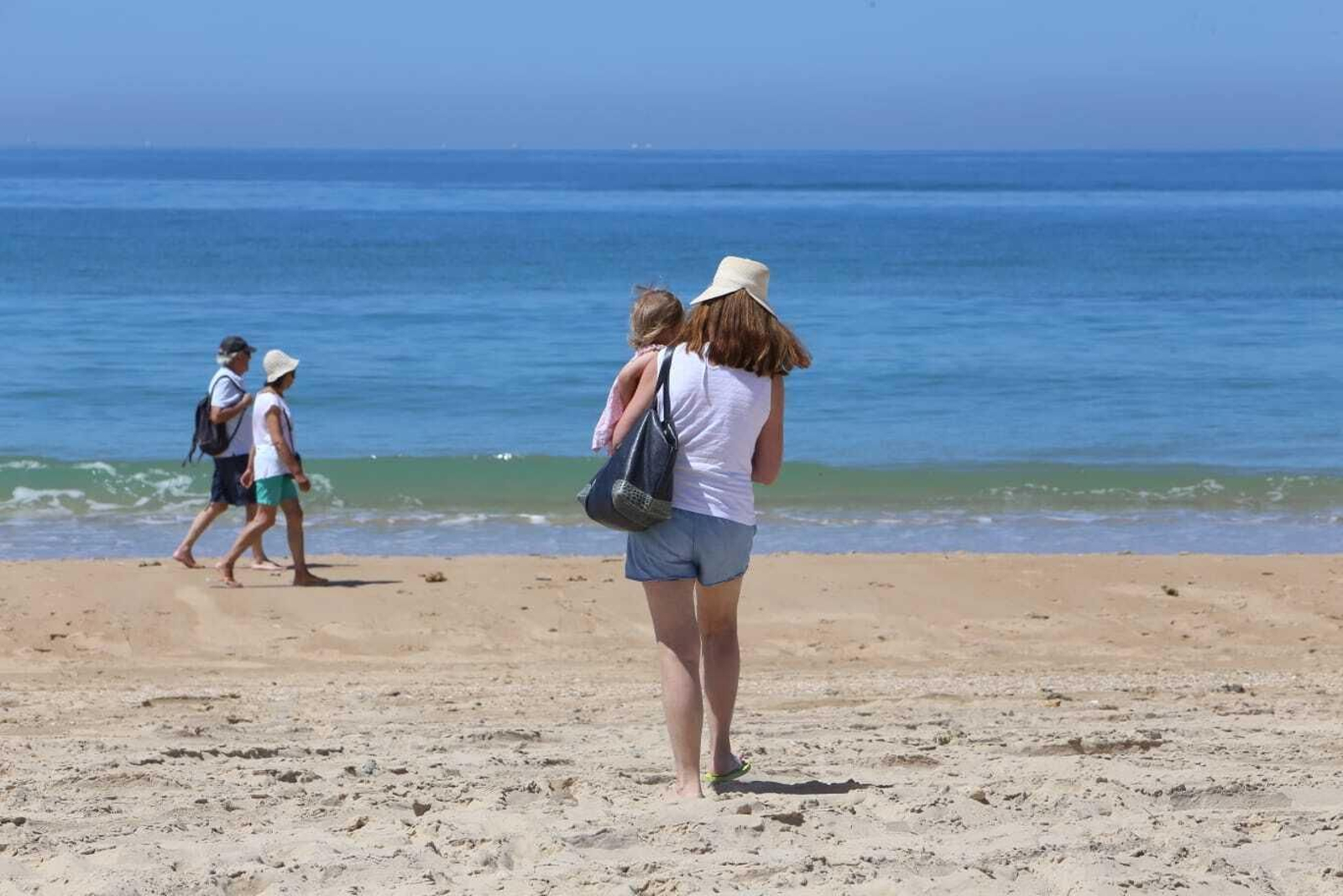 Personas paseando esta mañana por la arena de la playa de La Barrosa.