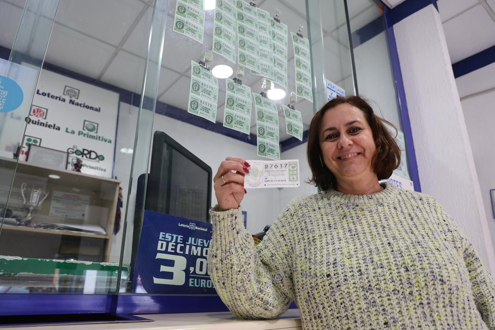 La lotera muestra un décimo con el número premiado.