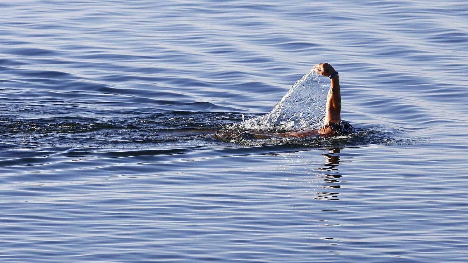 Una persona nada en el mar en la mañana de domingo.