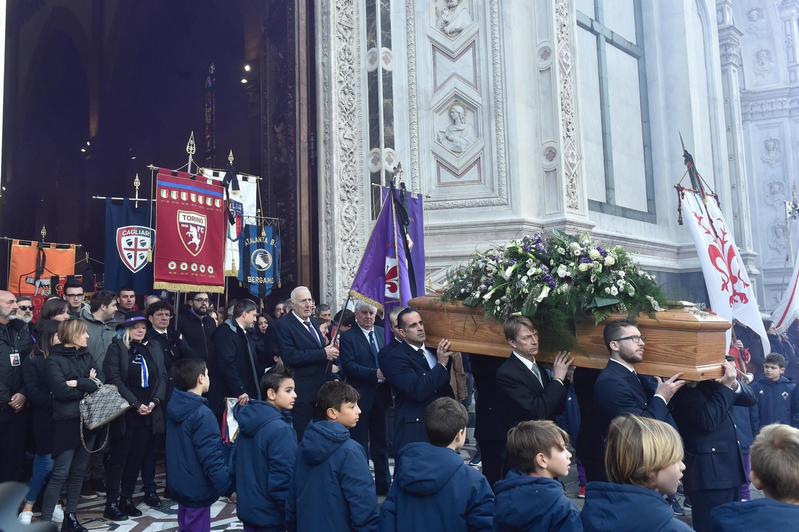 El féretro de Astori sale de Santa Croce con diferentes estandartes de clubes de fútbol detrás.