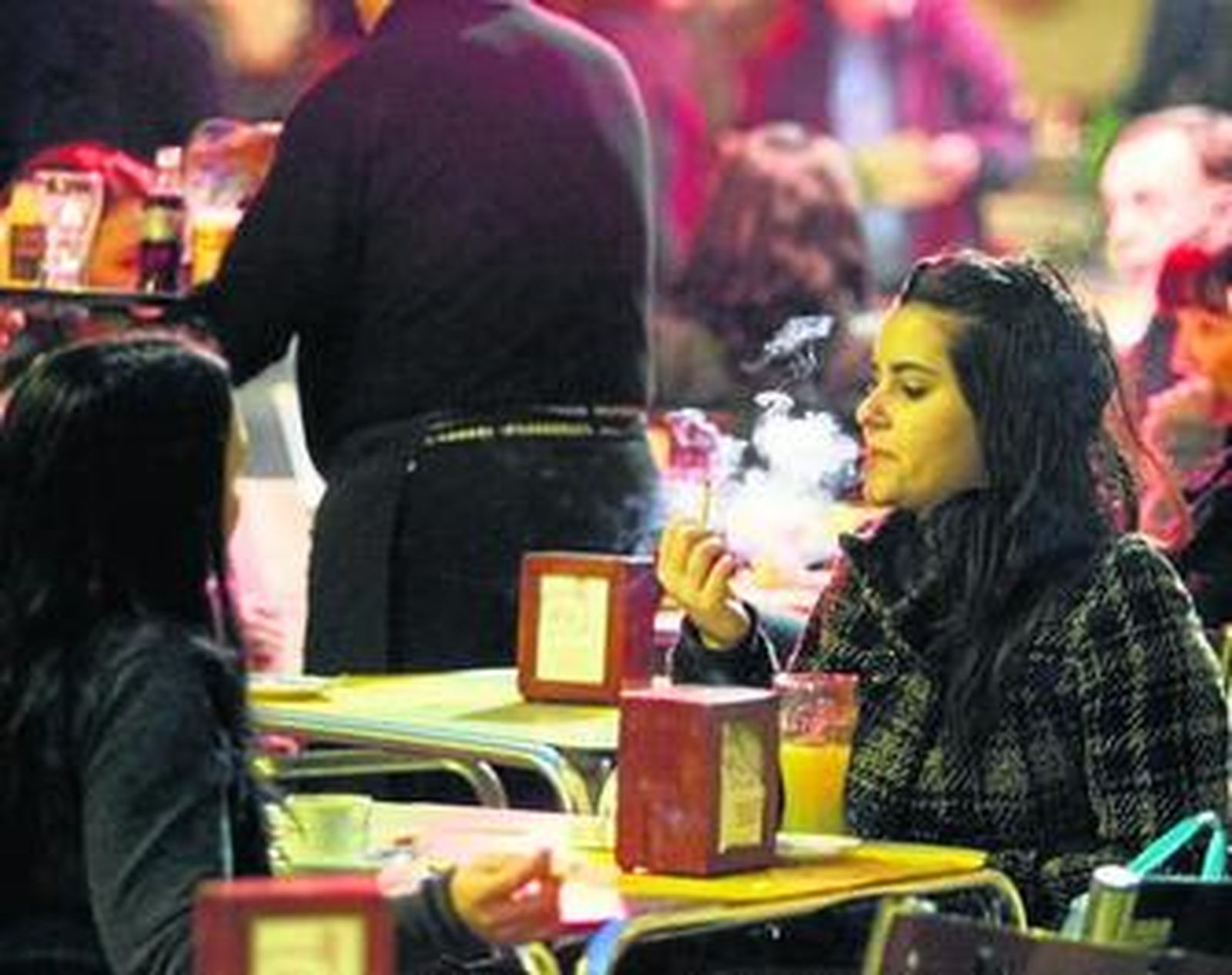 Una joven fumando en un velador de un establecimiento en el centro.