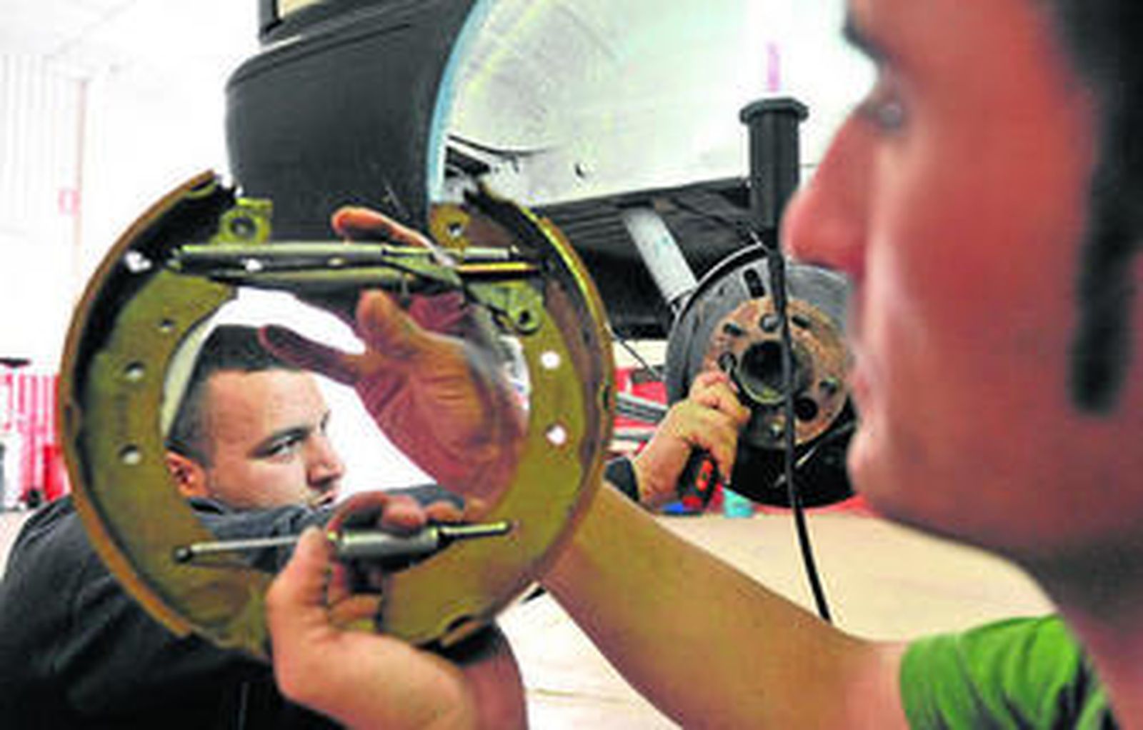 Un cliente repara su vehículo con la ayuda del mecánico.