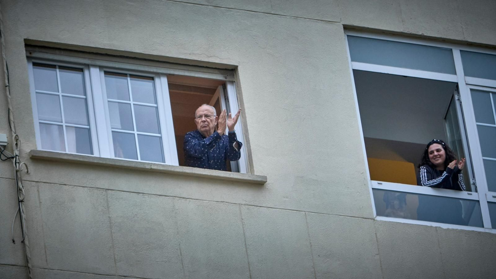 Dos vecinos salen a aplaudir enfrente del Puerta del Mar.
