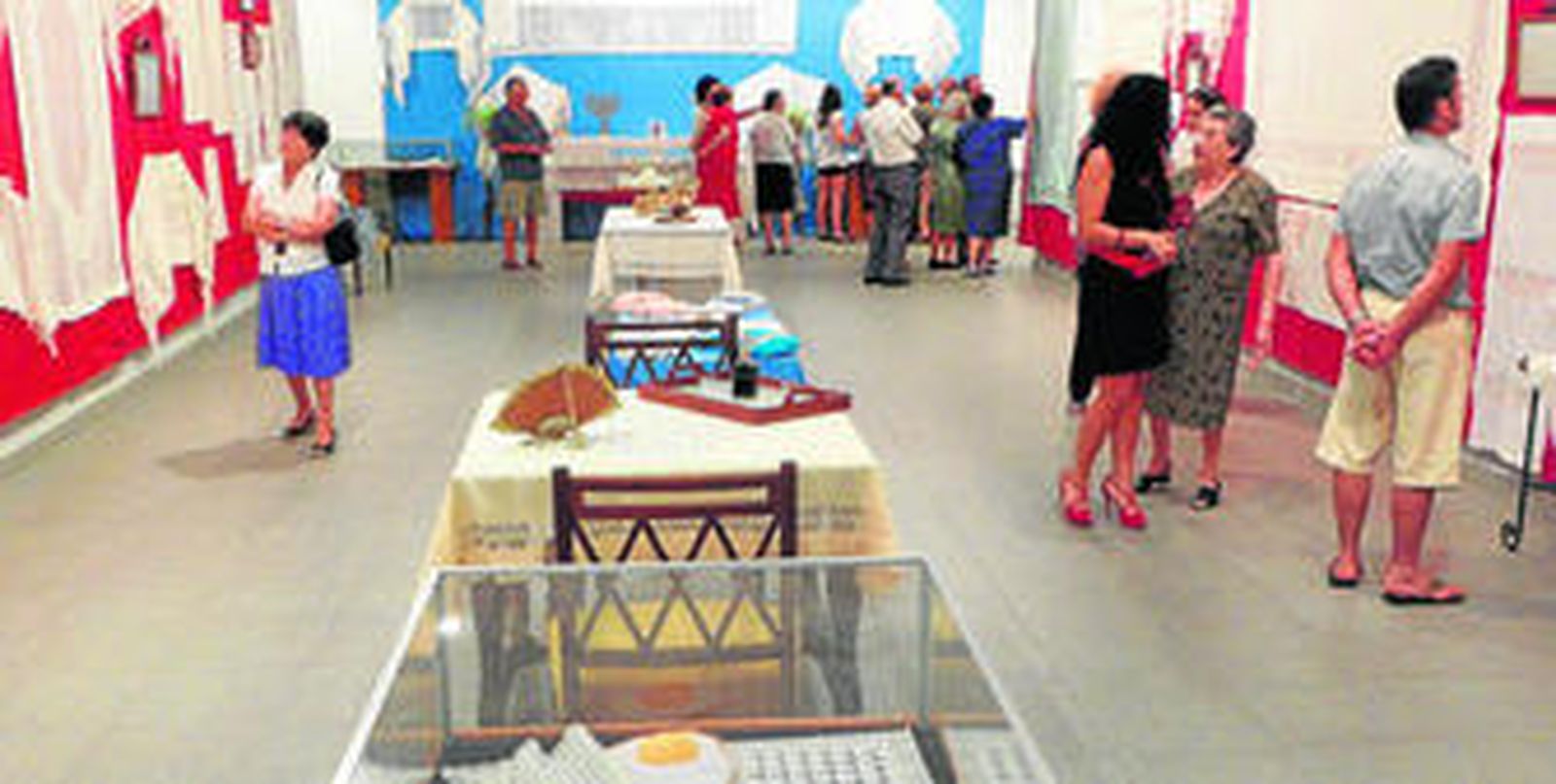 Sala del Teatro Sierra de Aracena, con la exposición de costura y sus visitantes.