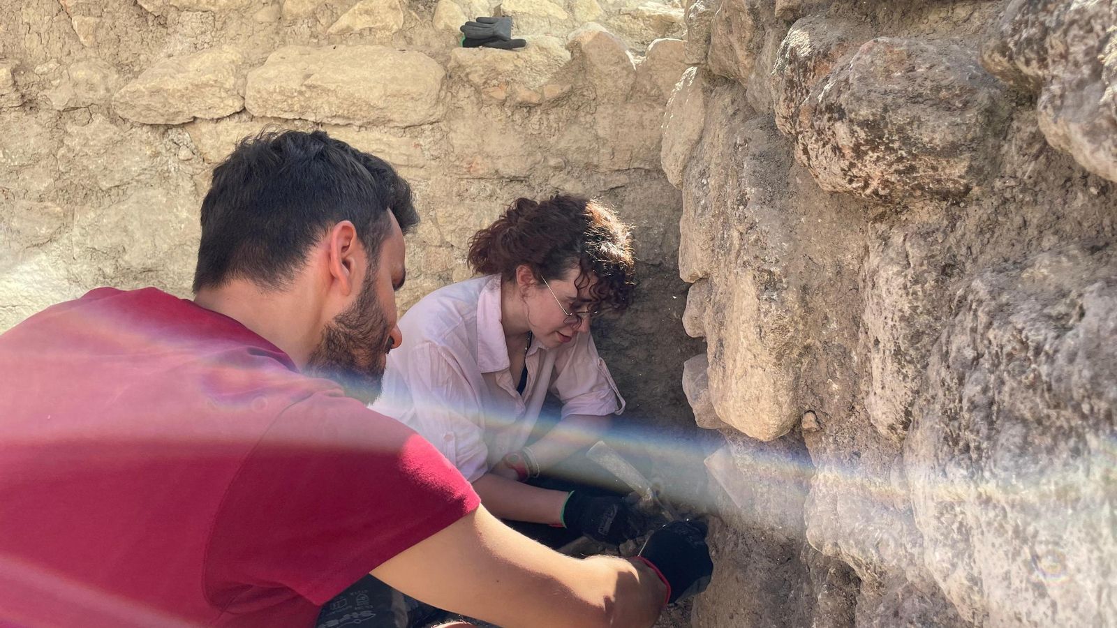 Dos voluntarios eliminan el estrato estéril en una pared de una habitación en El Toril.