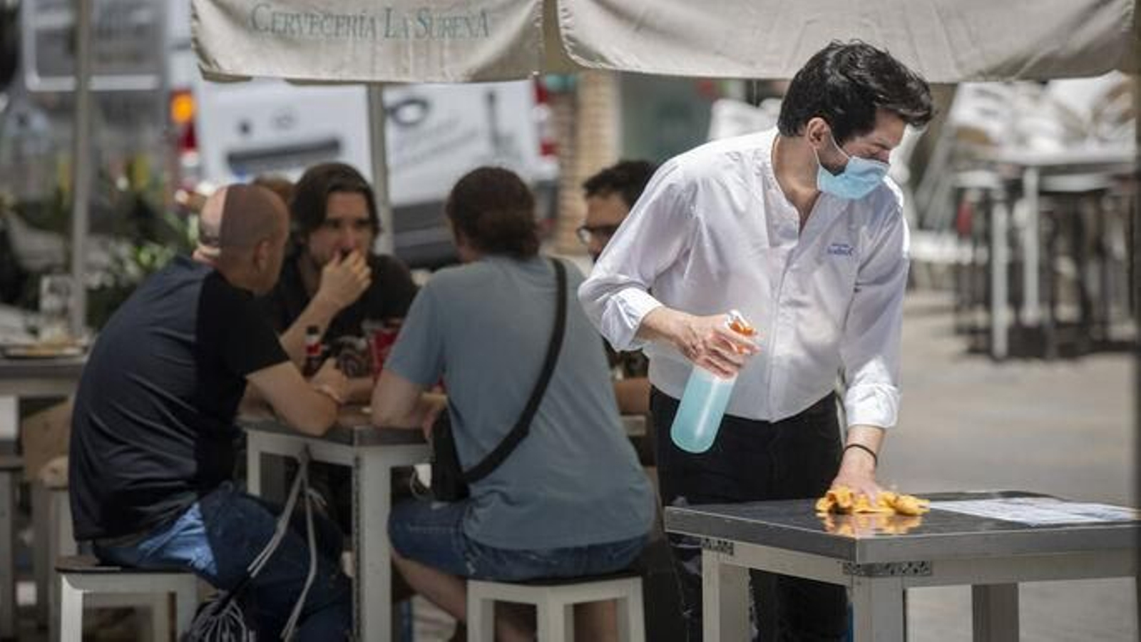 Camarero desinfectando una mesa para que sea ocupada por la clientela