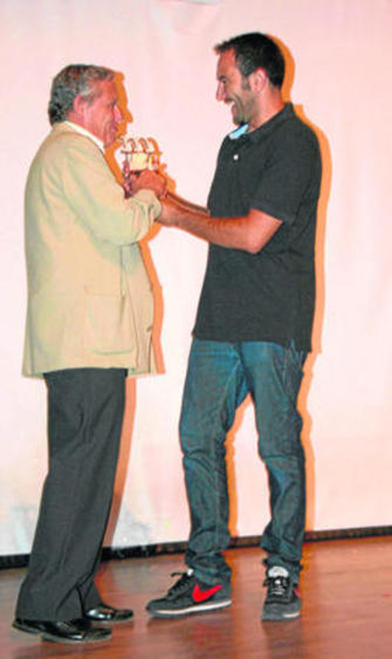 El alcalde entrega el galardón a uno de los integrantes de la compañía.