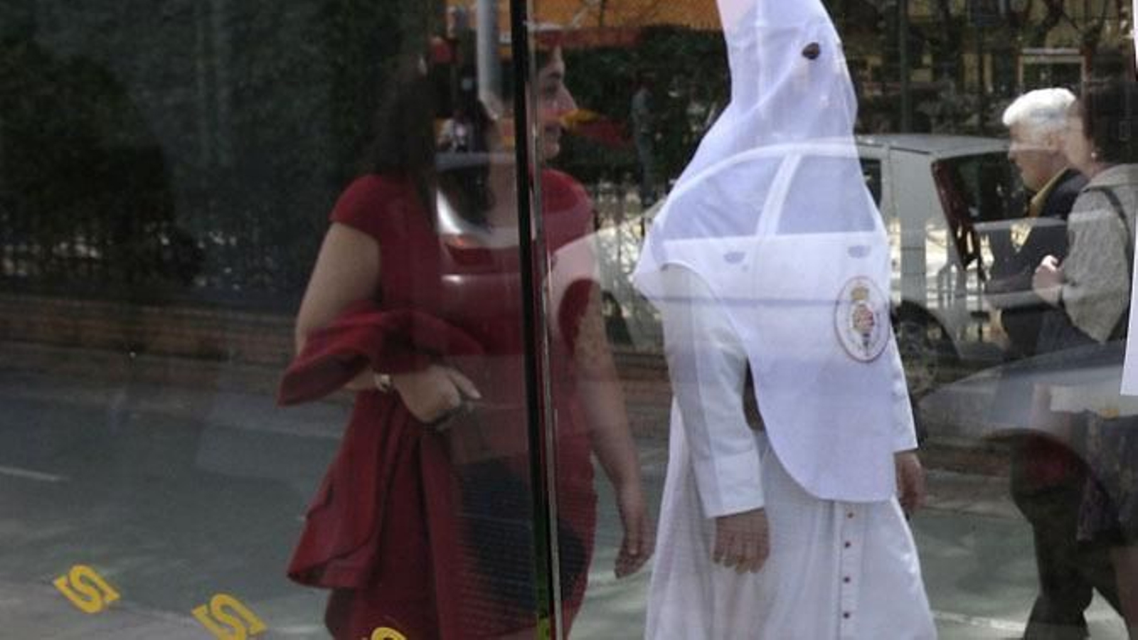 Un nazareno pasa ante una parada de Tussam