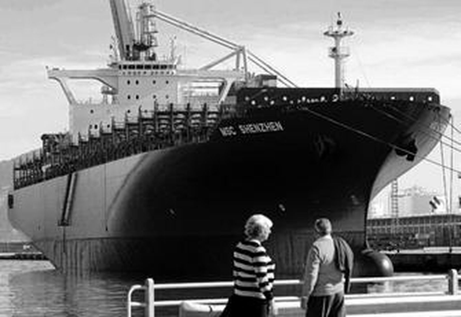 Una pareja contempla el 'Shenzhen' al fondo, ya de color azul, ayer en Isla Verde.
