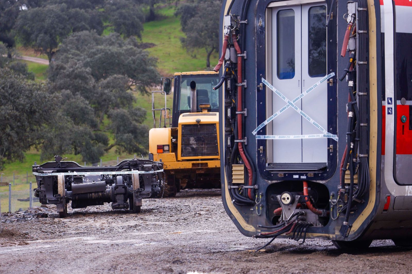 Un vagón del tren Iryo precintado, junto al bogie que se encontró en un arroyo cercano al lugar del accidente.