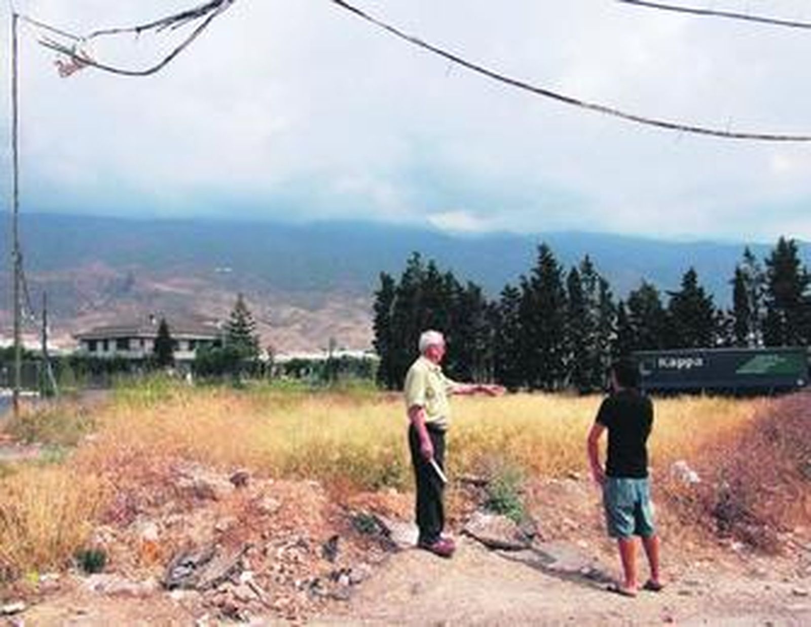 Dos vecinos señalan el solar convertido en improvisado vertedero.