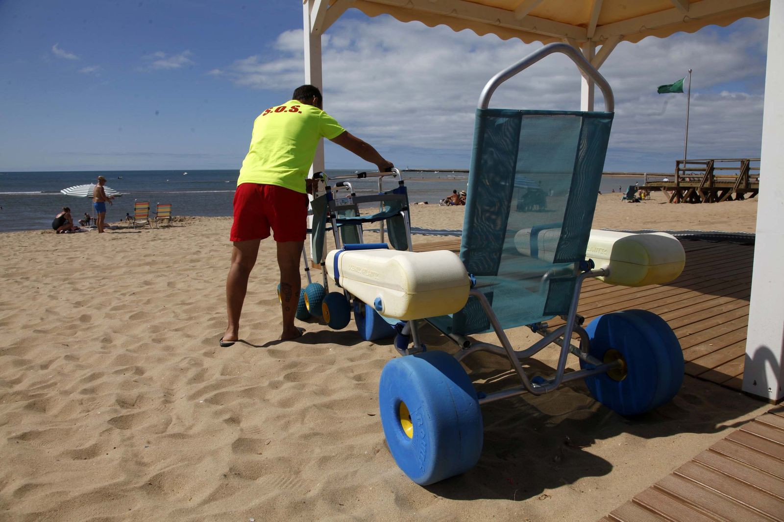 Un socorrista ordena el material para personas con discapacidad en una playa de Isla Cristina