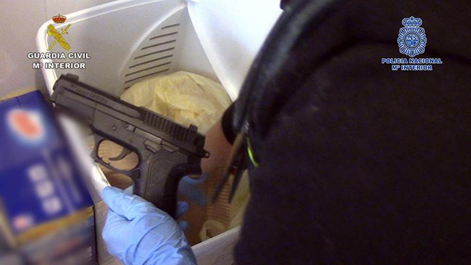 Una gente muestra una pistola encontrada en uno de los registros de la operación.